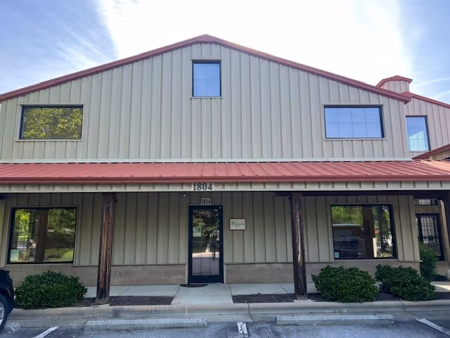 Exterior view of a BAYADA Pediatrics facility: metal siding, red roof, and glass entrance.