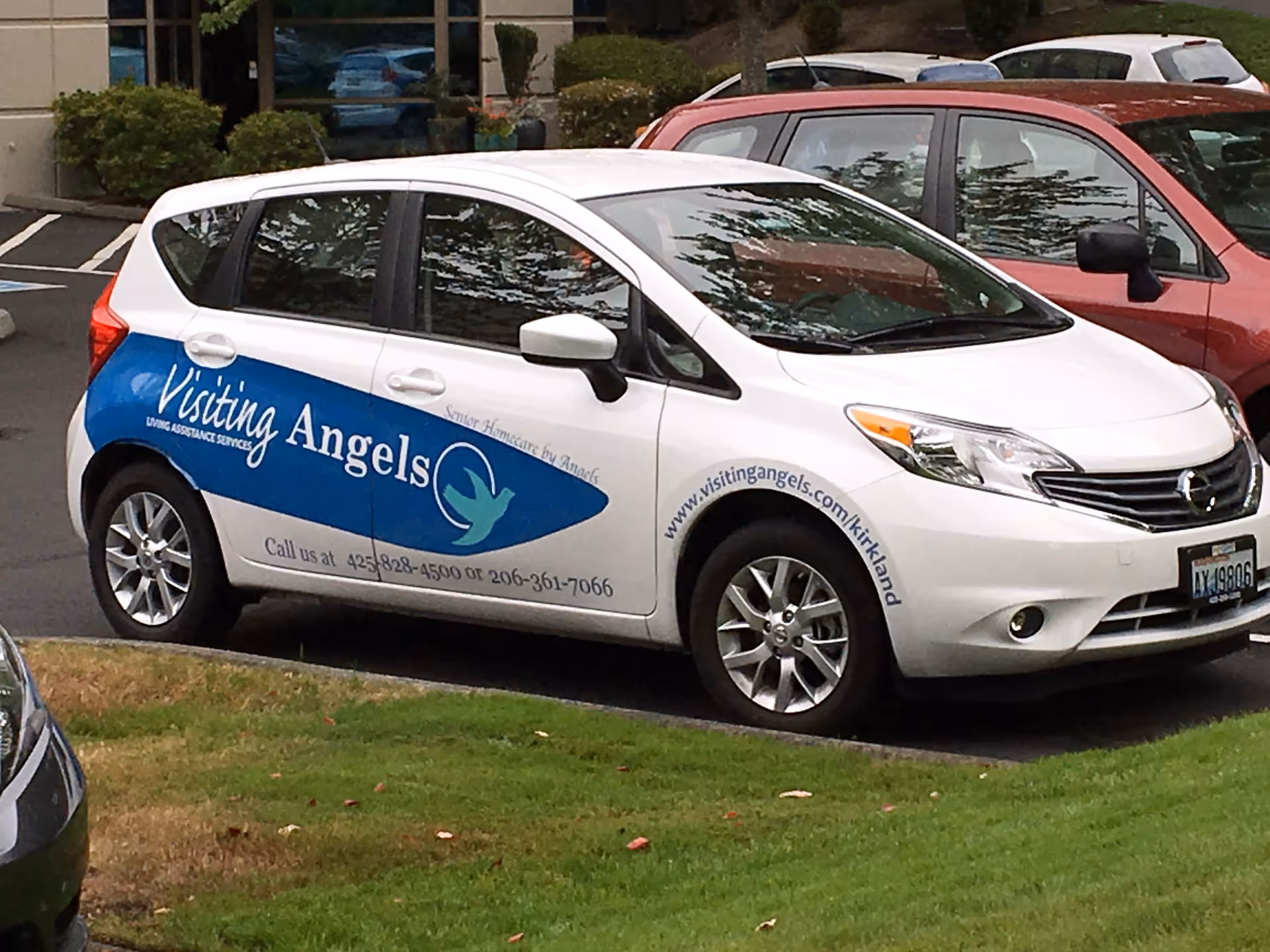 White Visiting Angels van with blue logo parked in a lot.