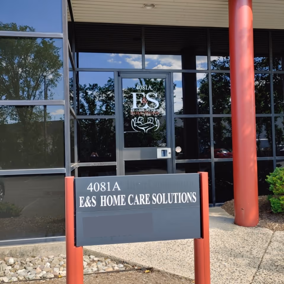 Front entrance of E&S Home Care Solutions with glass doors and red columns.
