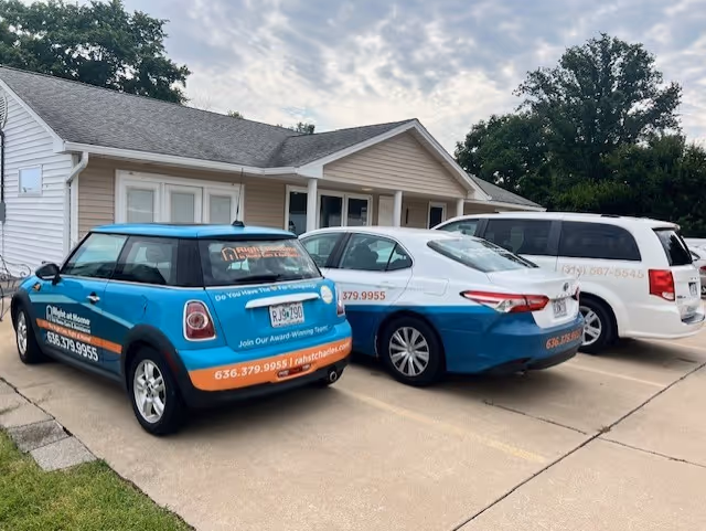 Three branded Right at Home vehicles parked in front of a building.