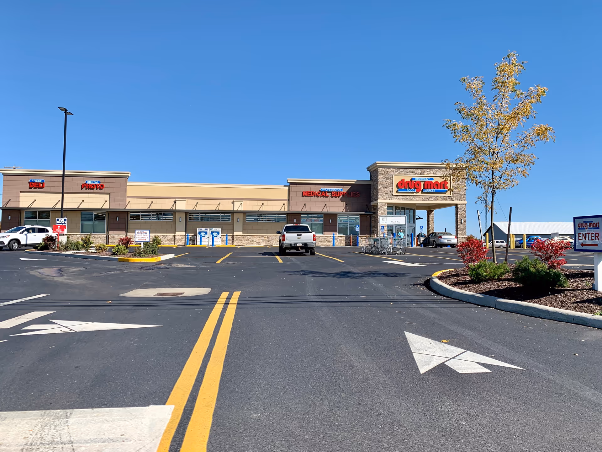 Exterior view of a Discount Drug Mart storefront with parking lot and blue sky.