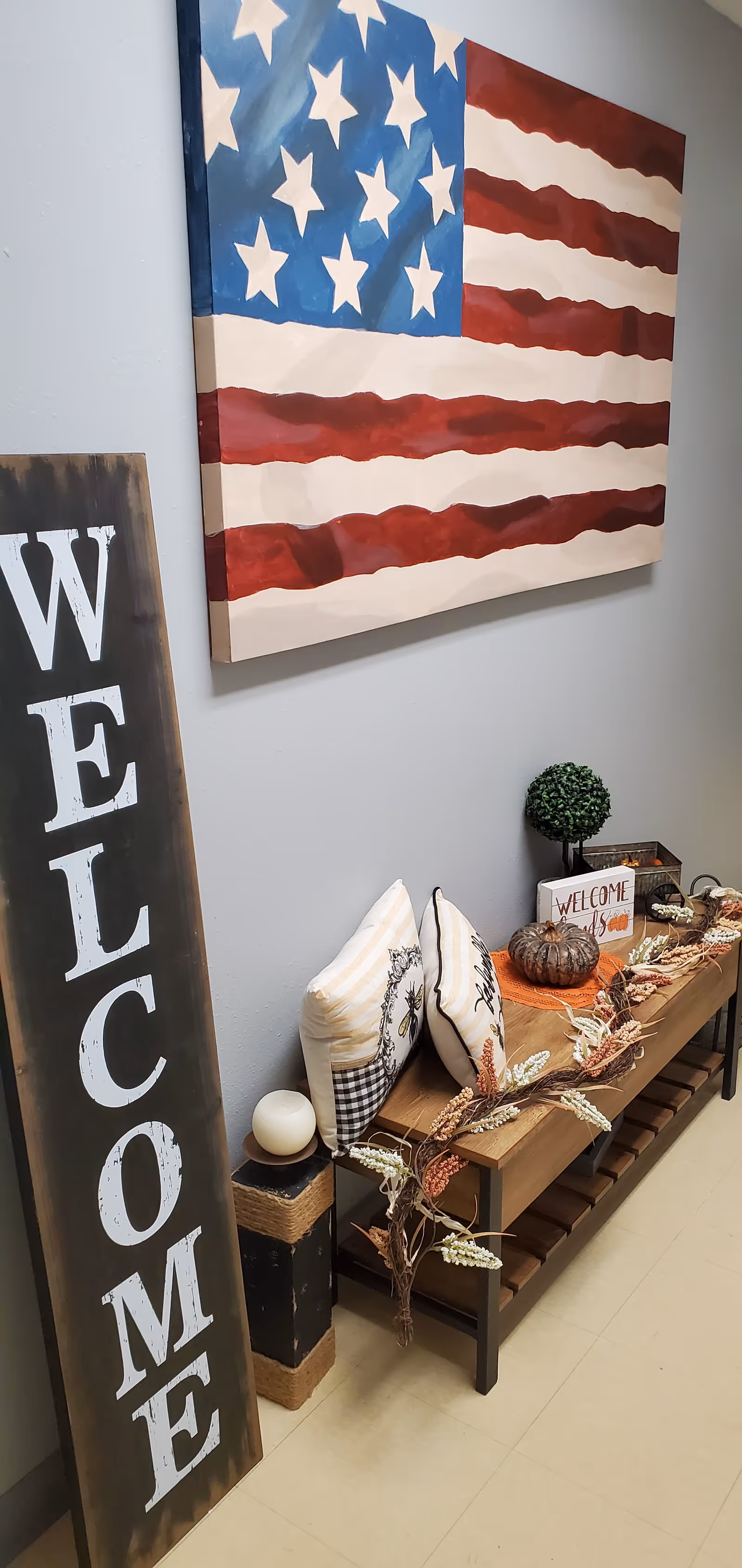 Interior hallway with a large American flag artwork, a tall vertical welcome sign, and cozy decor.