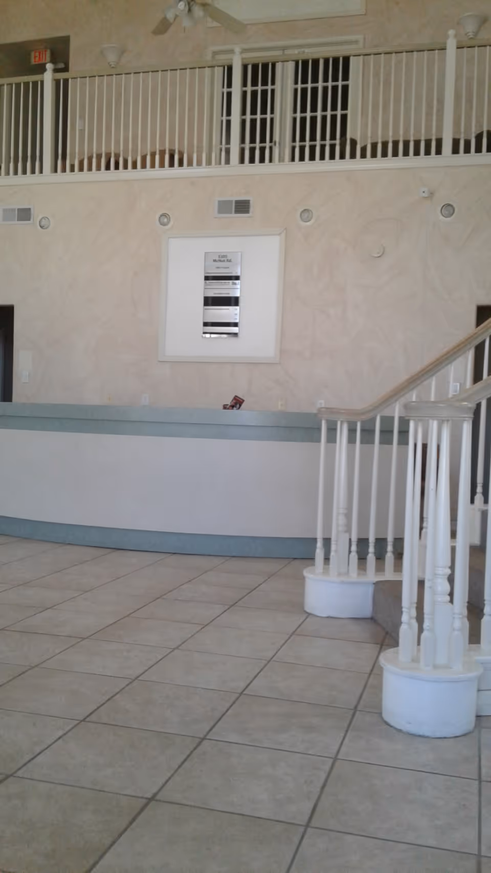 Interior of a senior living lobby with curved reception desk and staircase.