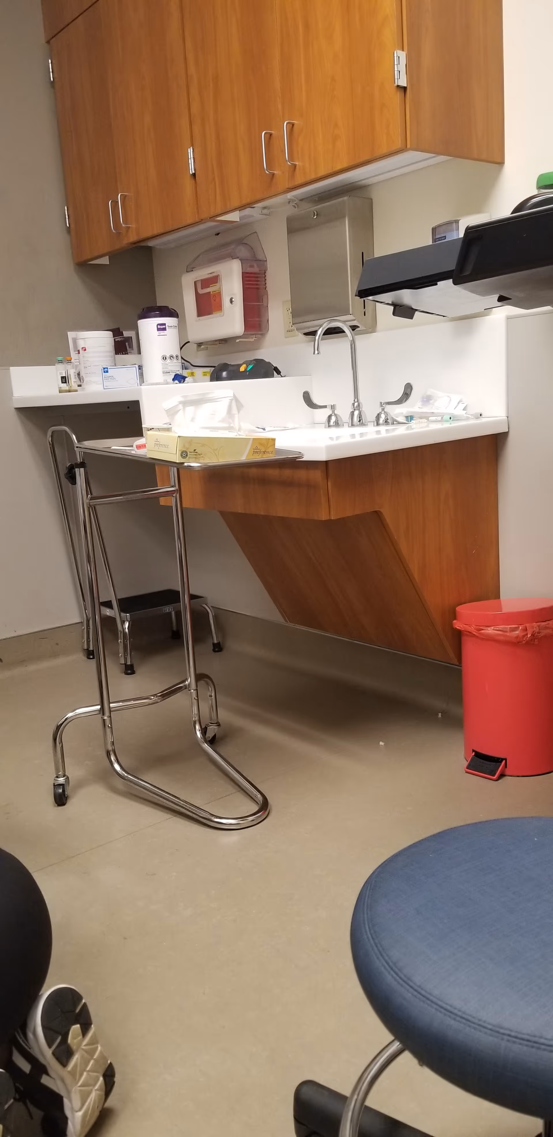 Clinic kitchenette with sink, wood cabinets, and medical supplies.