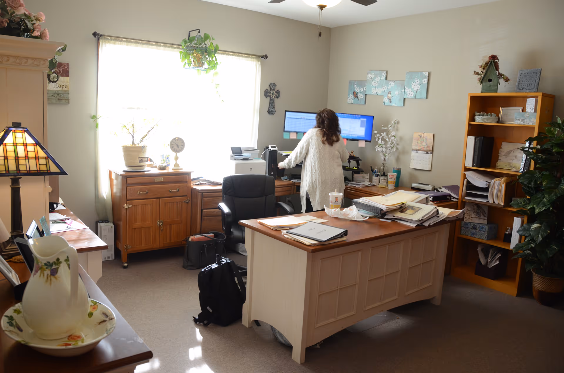 Staff workspace with computer, paperwork, and bookshelves in a bright homey office.