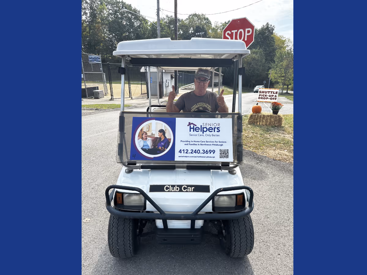 Senior Helpers promotional golf cart with a person giving thumbs up outdoors beside a stop sign.