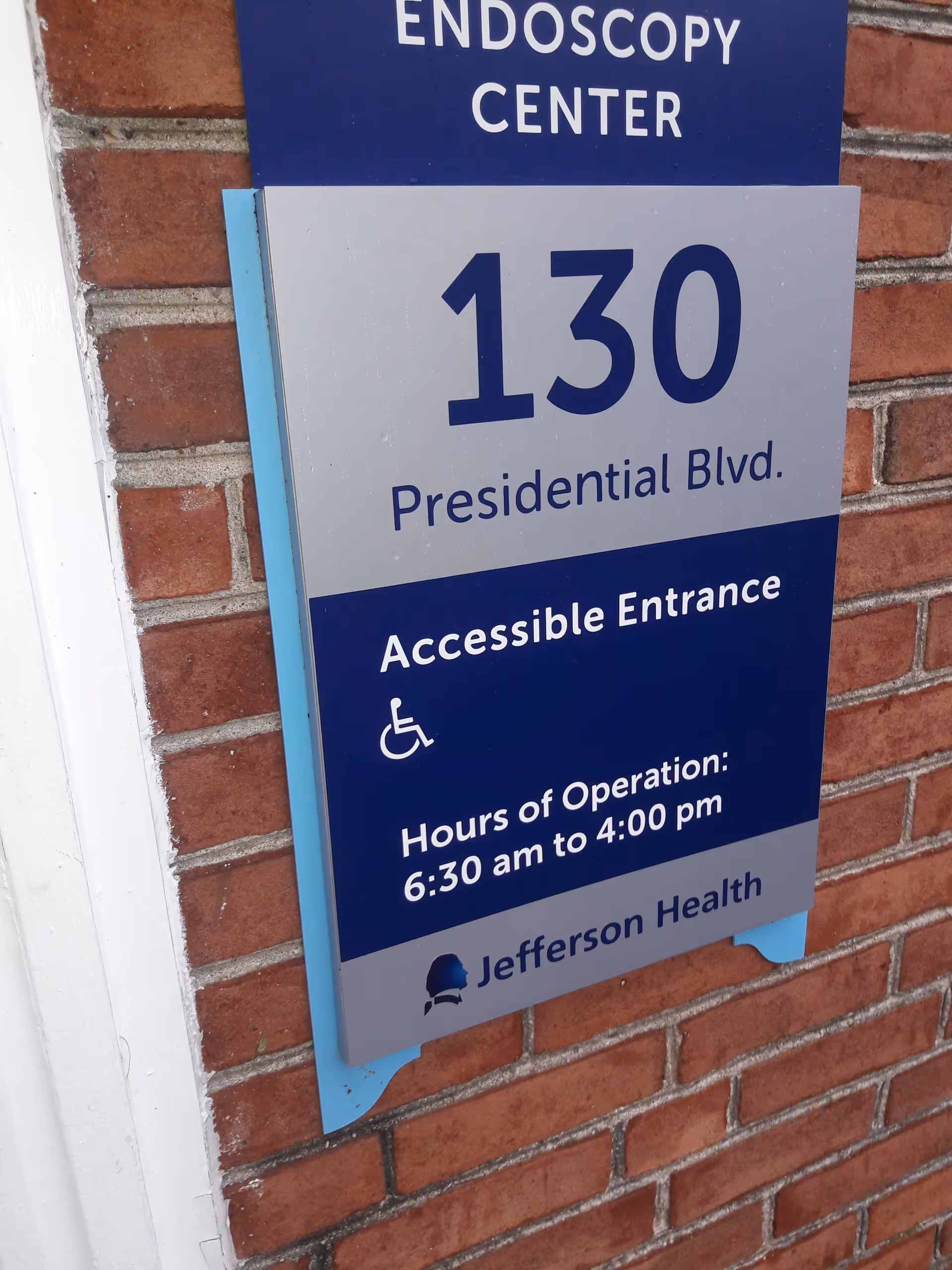 Blue and gray exterior sign on brick wall advertising an Endoscopy Center.