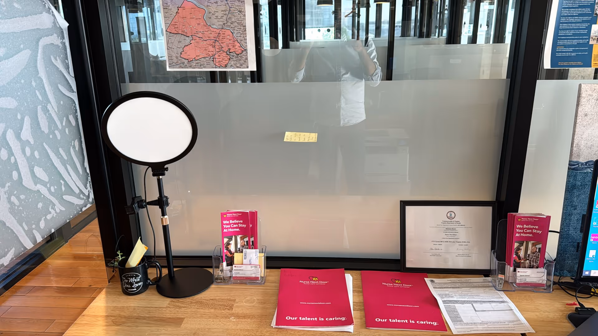 Reception desk area with a ring light, frosted glass partition, and brochures.