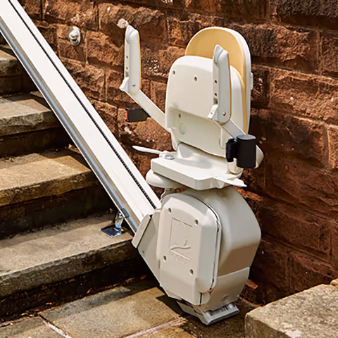 Outdoor stair lift mounted beside brick wall and steps outside facility.