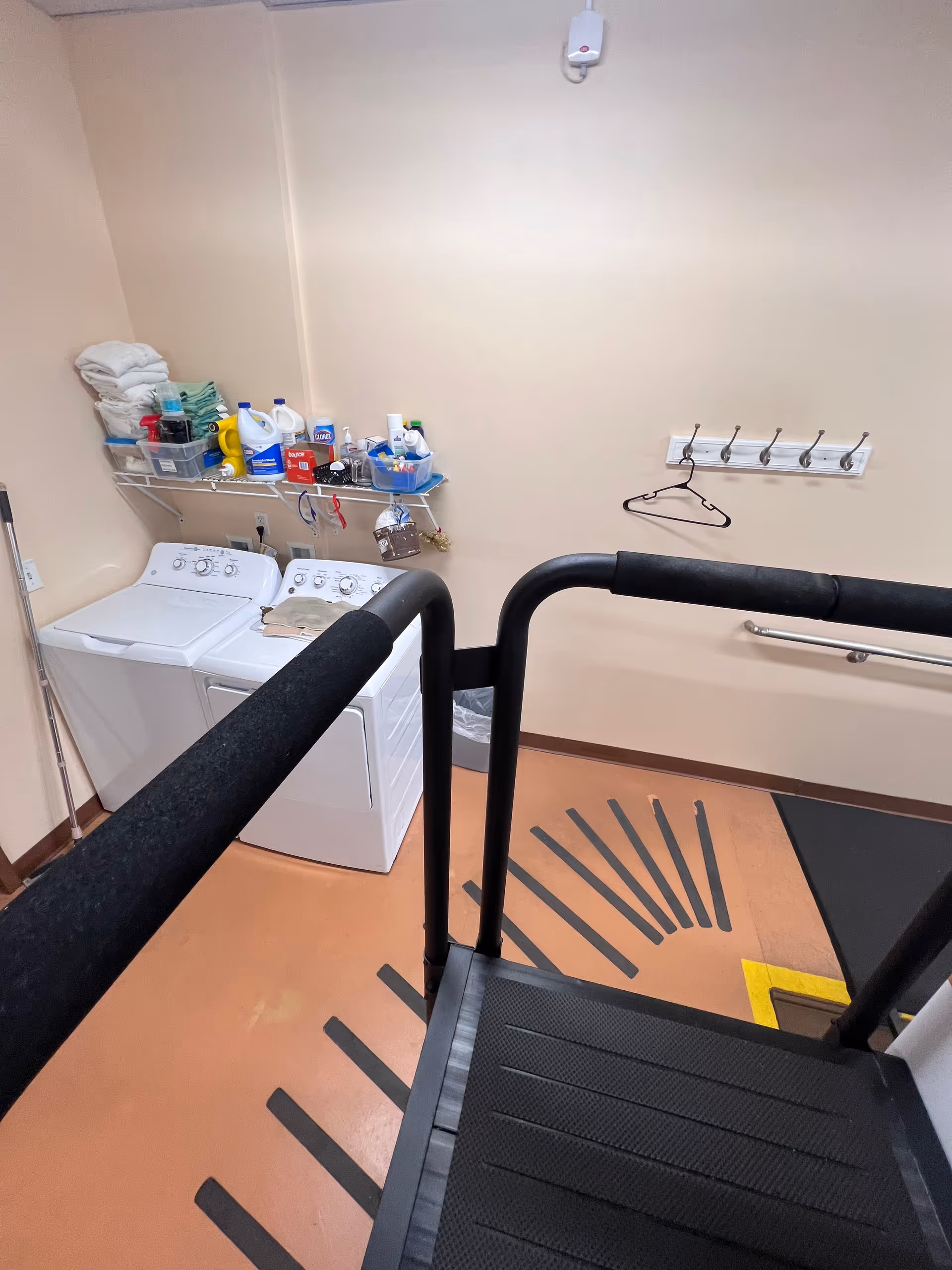 Interior laundry/utility room with washers, cleaning supplies, and a staircase railing.