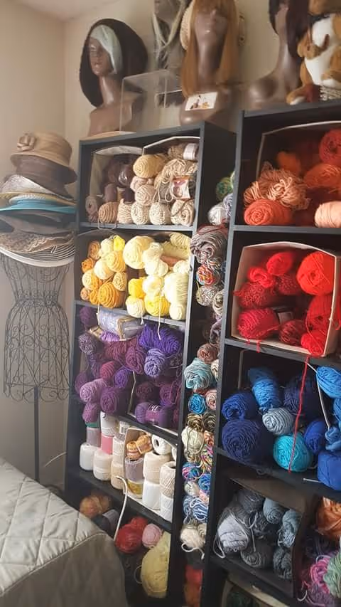 Colorful yarn skeins and mannequin heads in a craft room.
