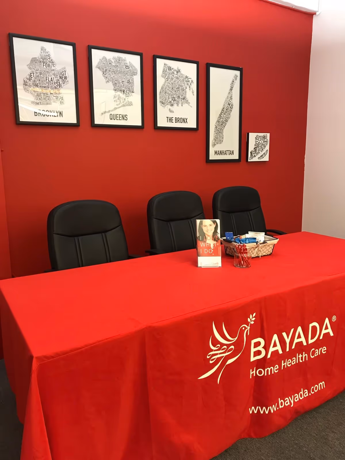 Red-walled reception area with a BAYADA table, black chairs, and wall art.