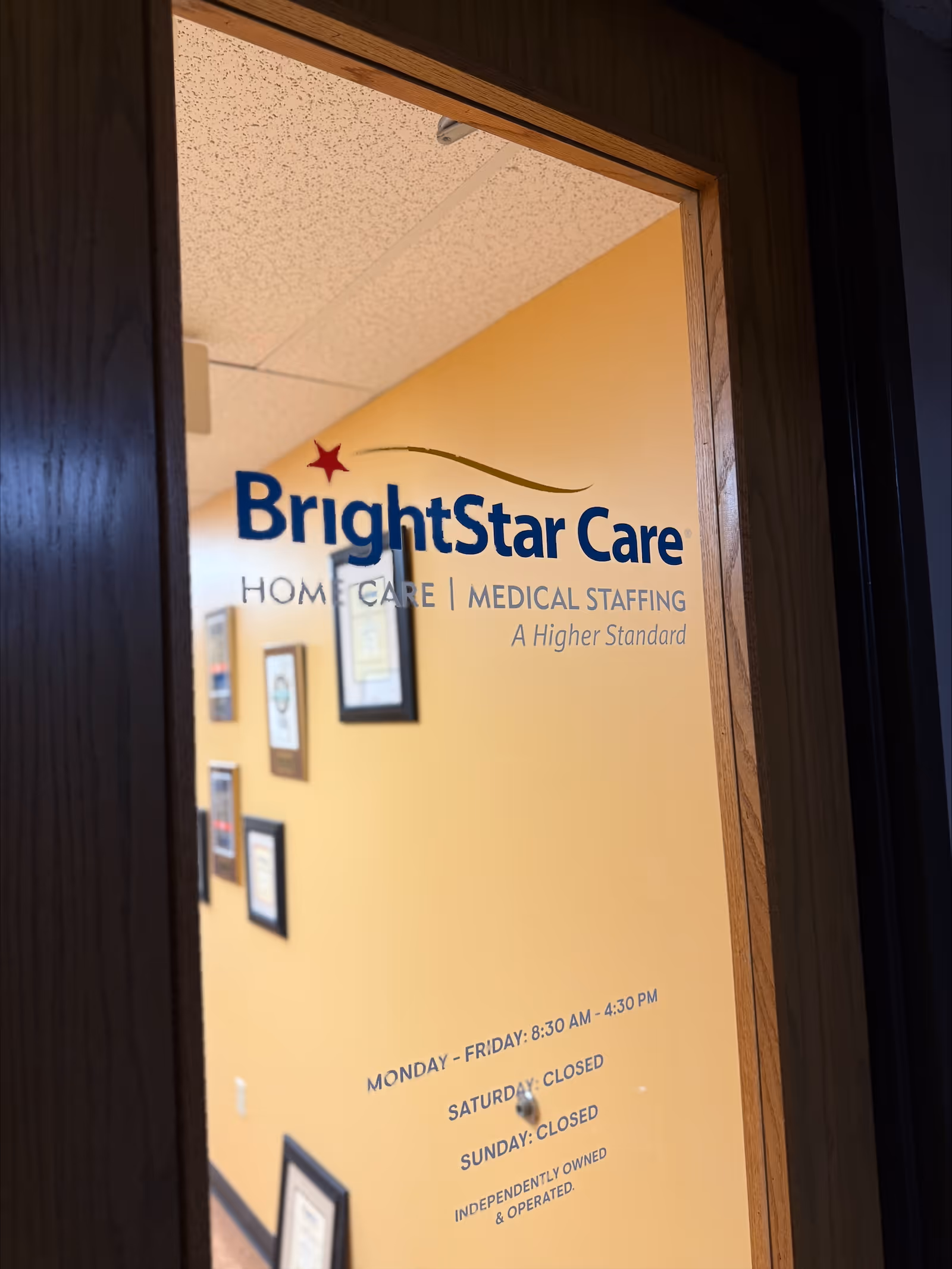 Interior doorway shows BrightStar Care sign and framed certificates along a hallway wall.