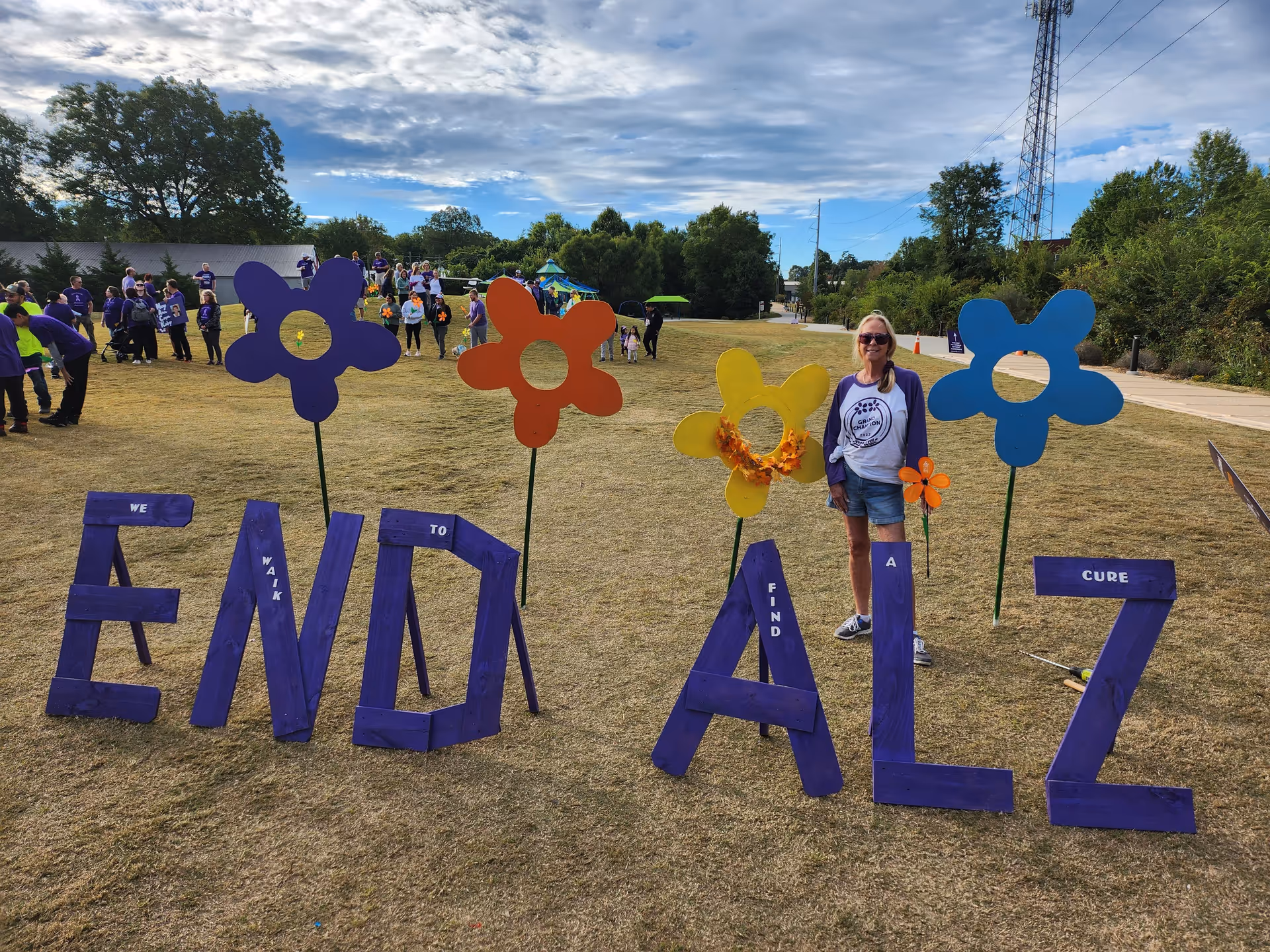 Outdoor event with large purple ENDALZ letters and colorful flower cutouts.