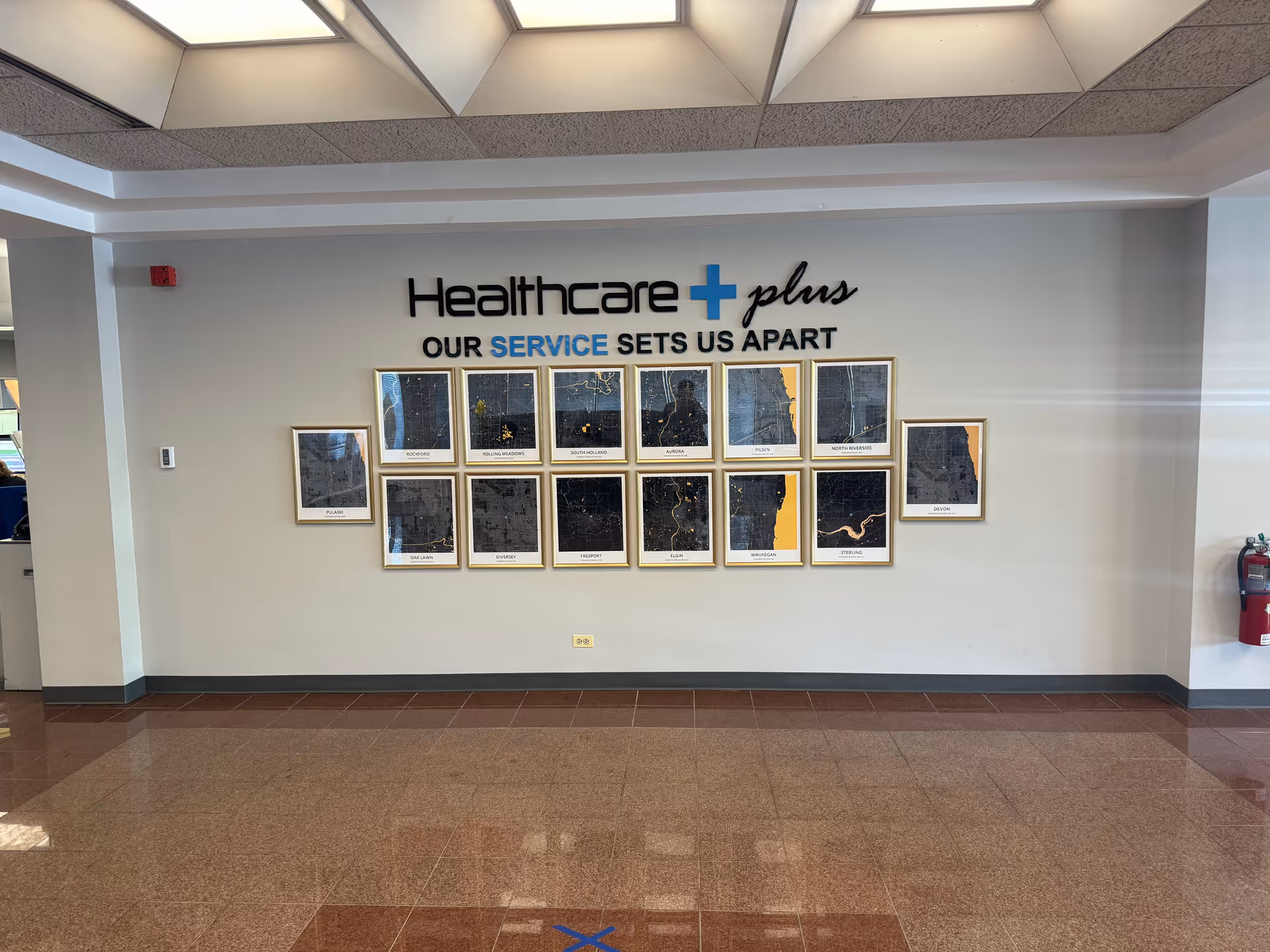 Interior lobby wall with framed pictures and a Healthcare Plus sign.