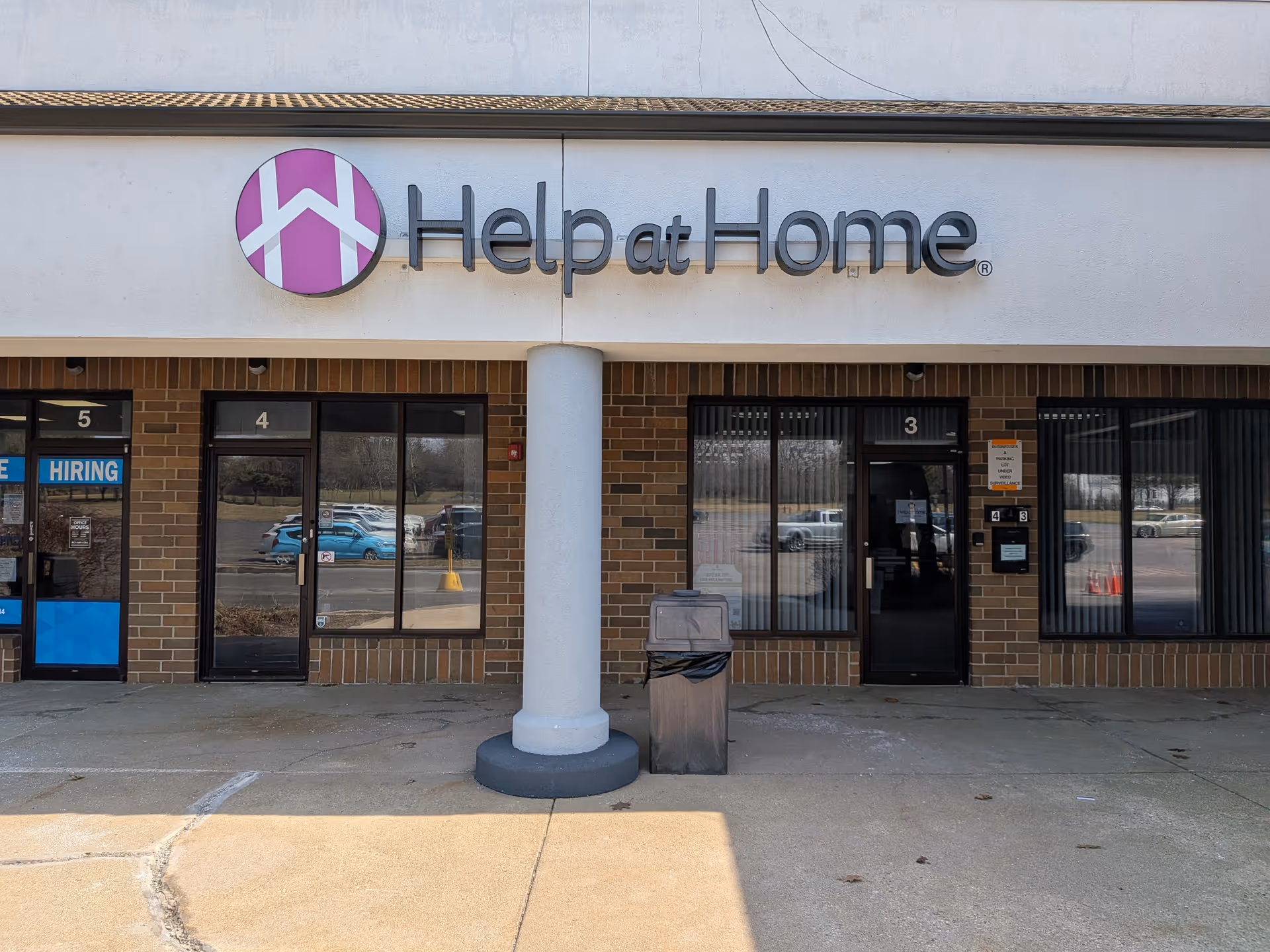 Front of a Help at Home storefront with logo sign, brick facade, and glass doors.