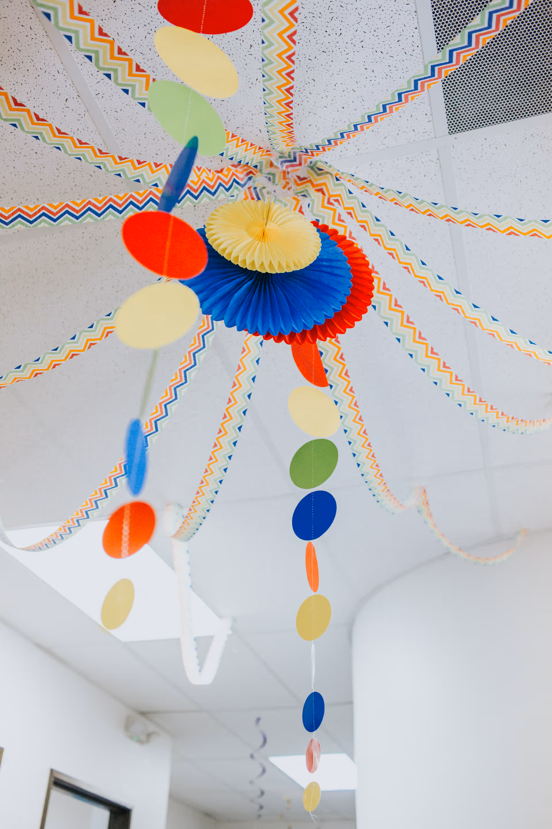 Colorful paper decorations hang from the ceiling in a bright hallway interior.