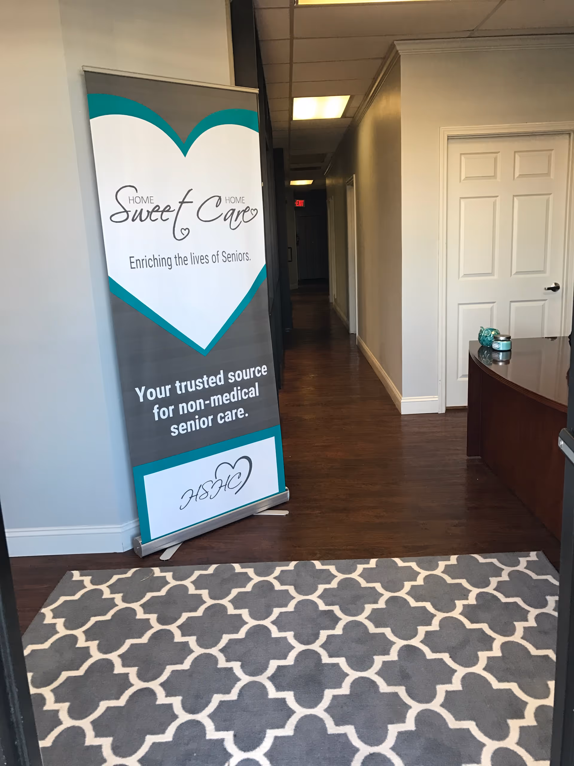 Interior hallway of a senior care facility with a banner and patterned rug.