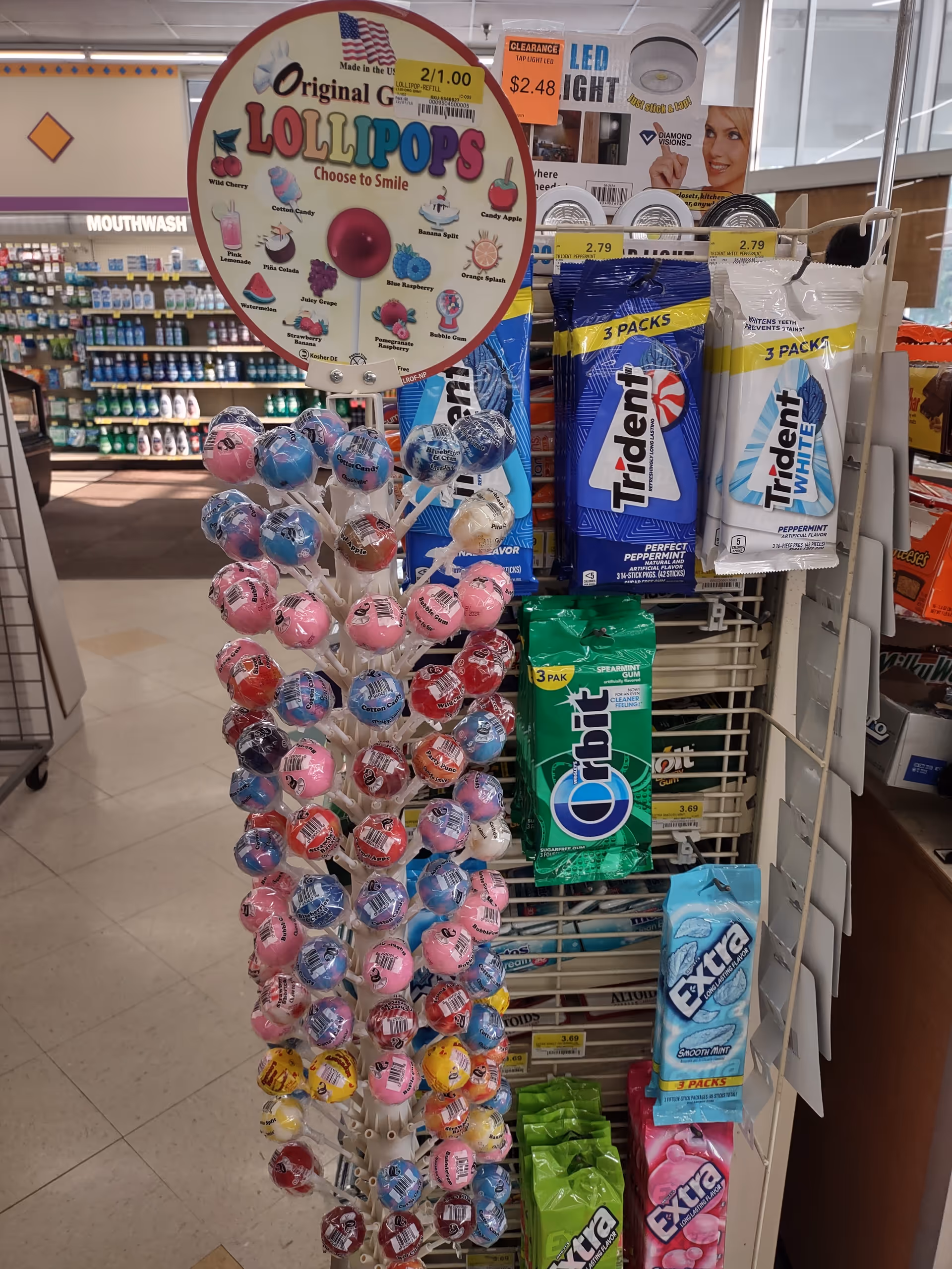 Circular lollipop display with toothpaste and oral care products in a drugstore aisle.