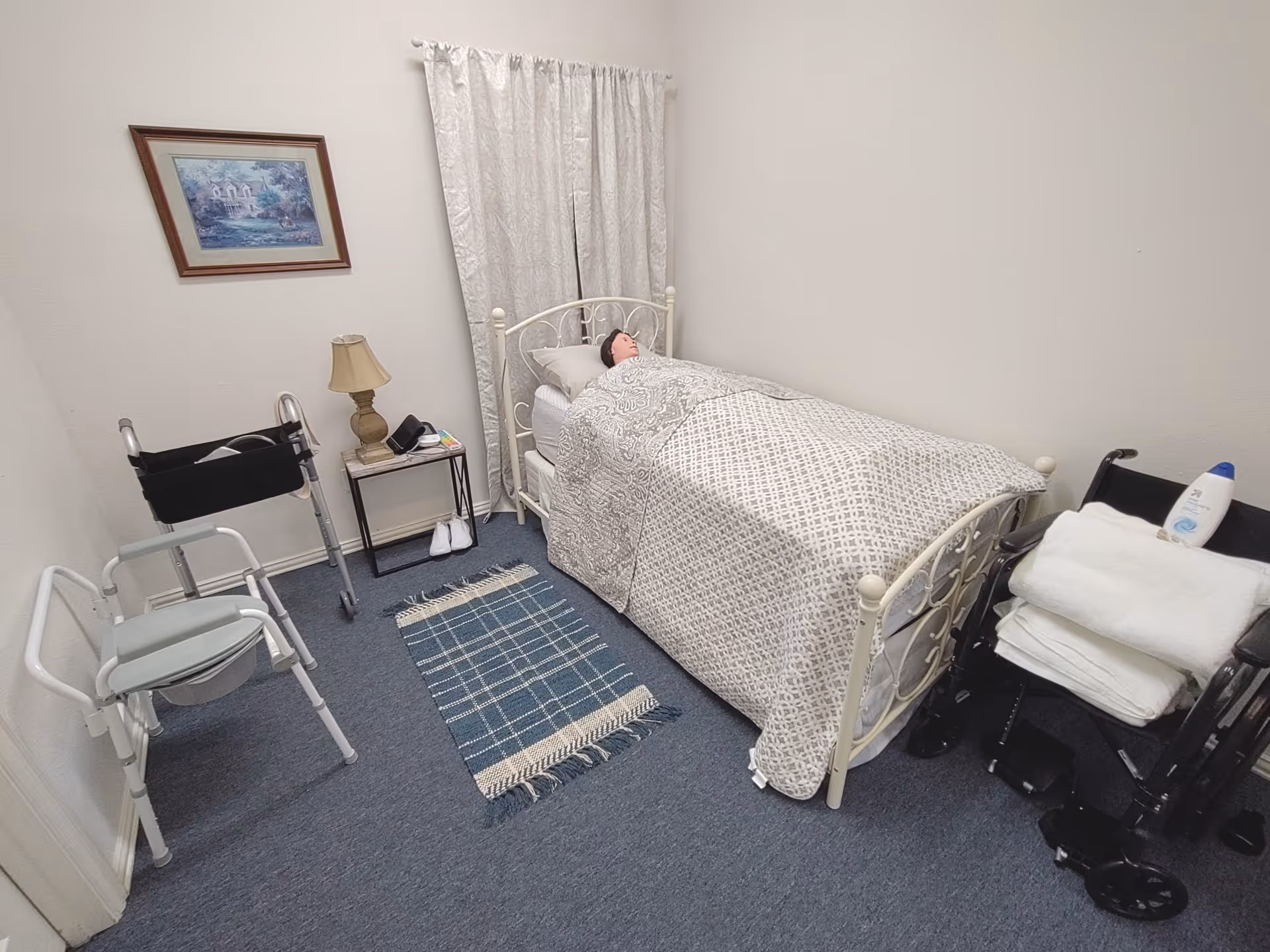 A small senior living bedroom with a patient in bed, mobility aids, and a nightstand.