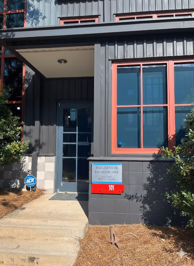 Exterior view of BrightStar Care building entrance with blue door and red-framed windows.