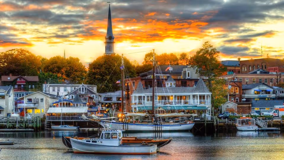 Sunset over a harbor town with boats docked along calm water