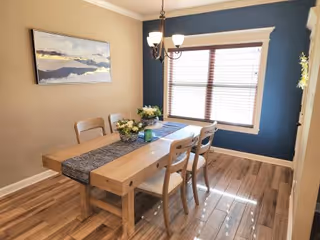 Bright wooden dining table with chairs in a beige and blue dining room.
