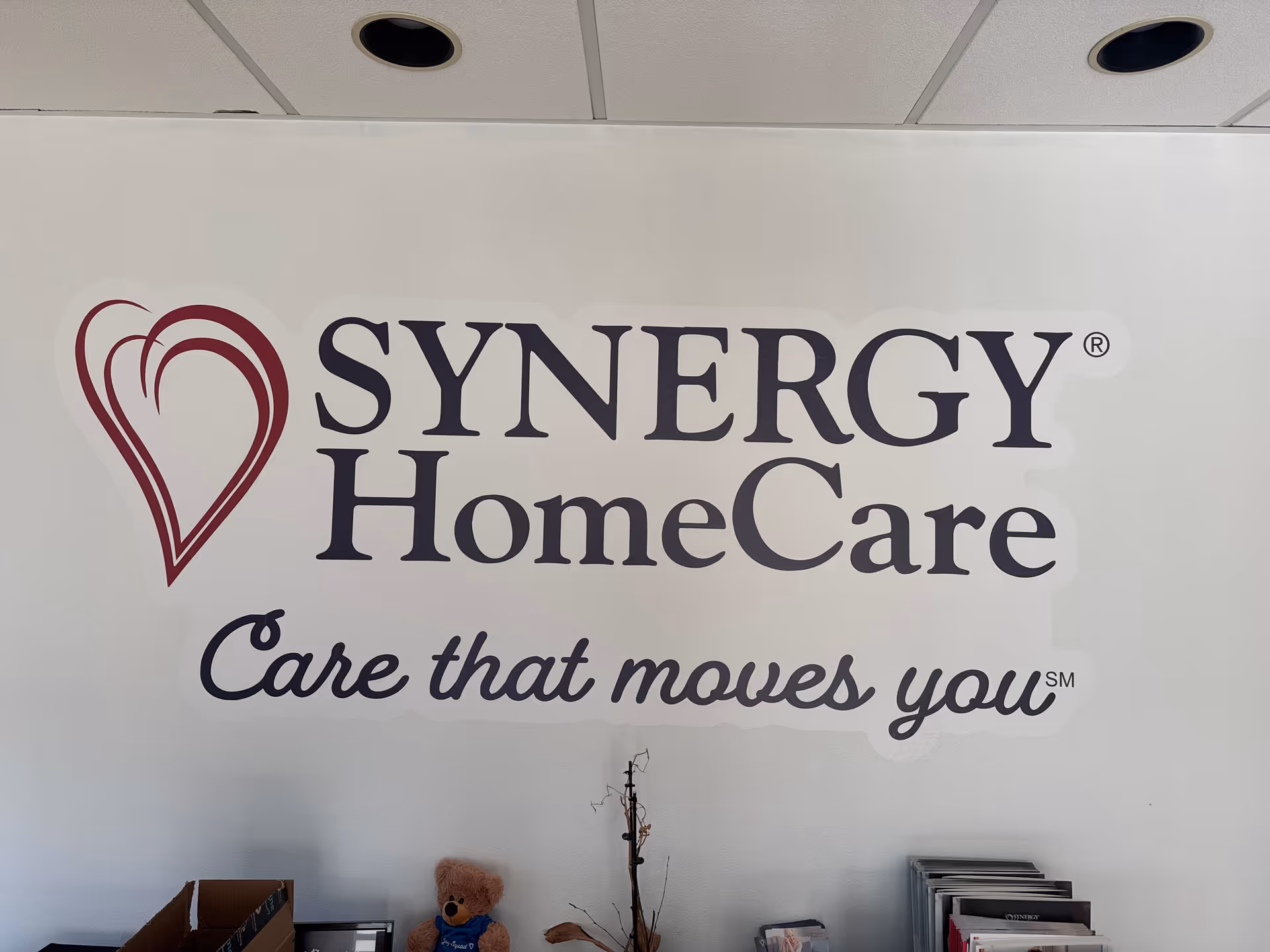 Interior wall featuring SYNERGY HomeCare logo and the slogan Care that moves you.