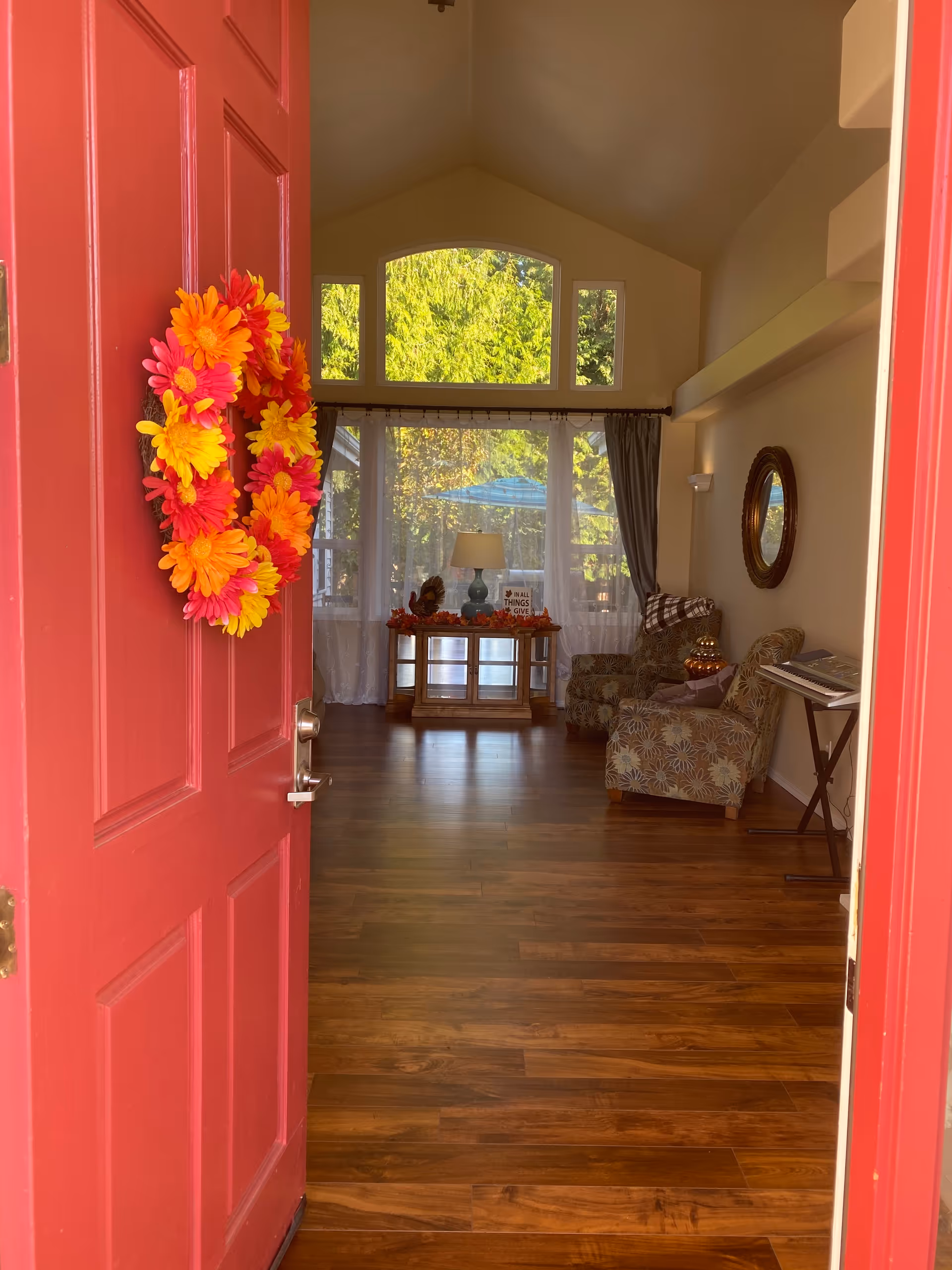 Red front door opens to a cozy living room with wood floors and seating.