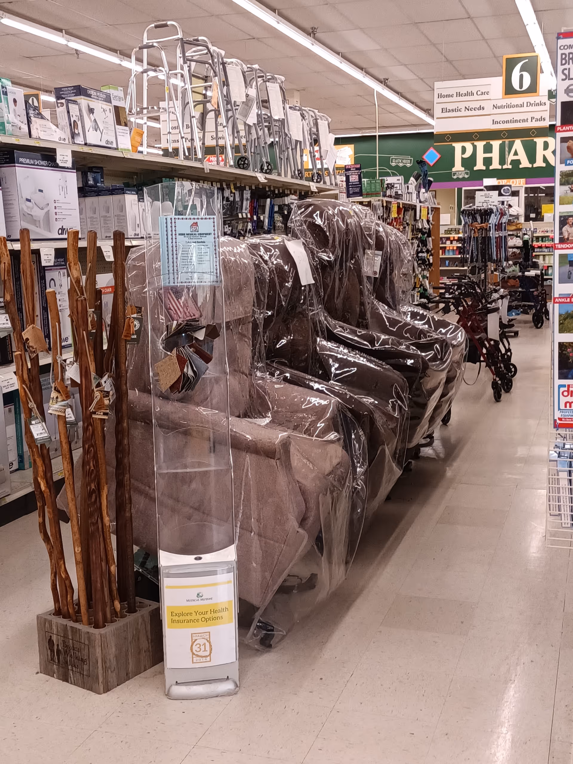 Aisle inside Discount Drug Mart with wrapped chairs and mobility aids on display