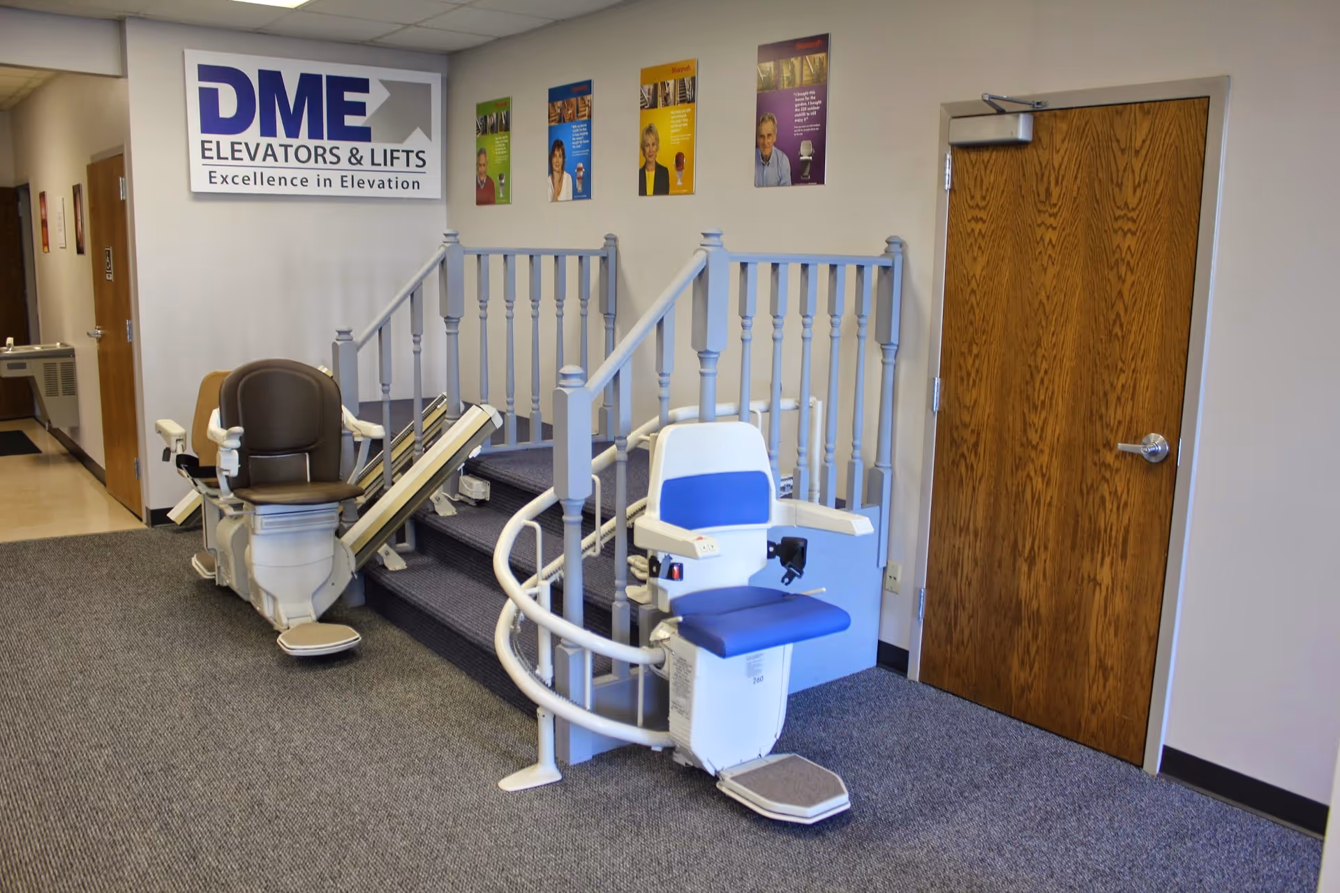 Interior hallway with stairlift chairs, gray railings, a wooden door, and a DME sign.