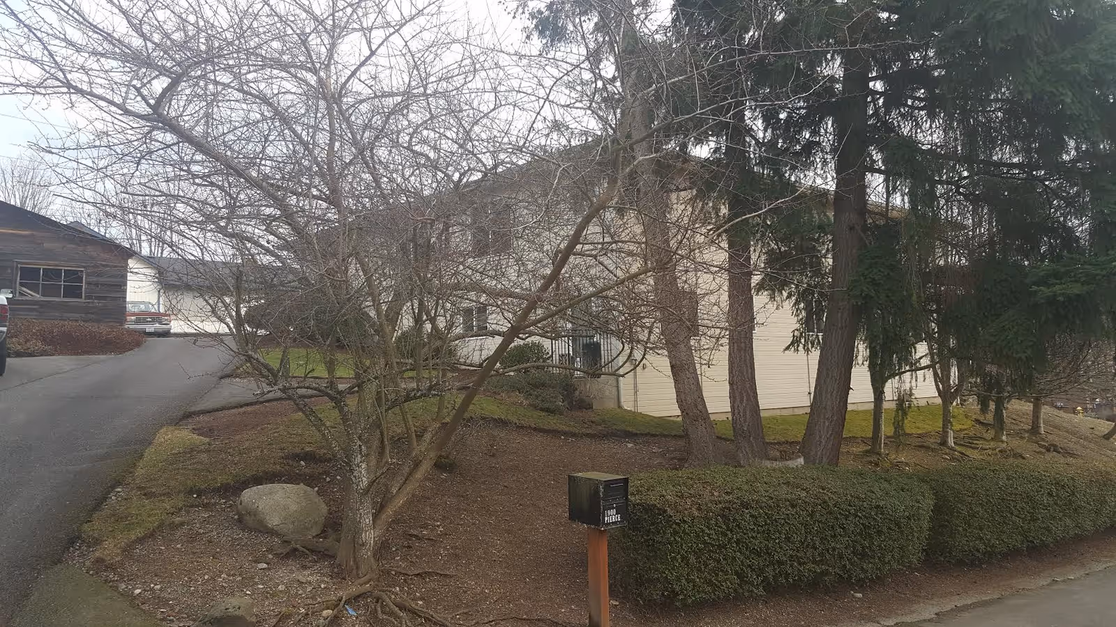 Exterior view of Heritage Home Care facility with trees, shrubs, and a driveway.