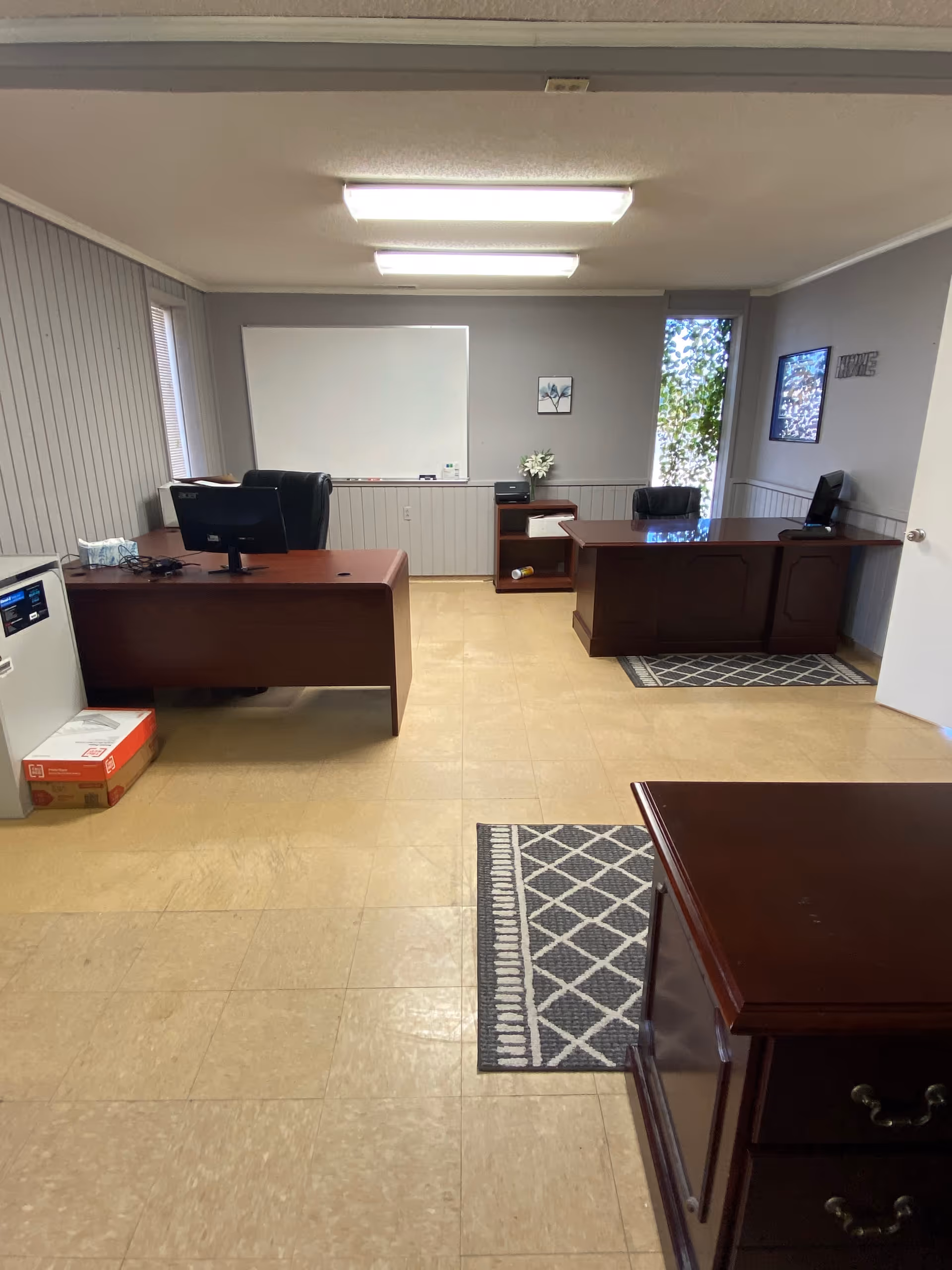 Interior office area with desks, computers, a whiteboard, and office furniture.