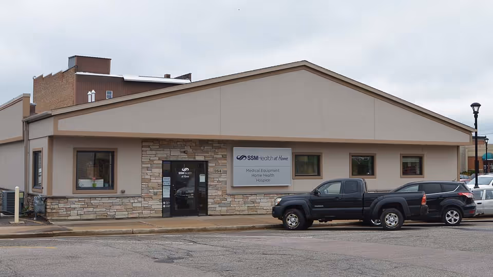 Single story building with SSM Health at Home sign, stone facade, and parked vehicles out front.