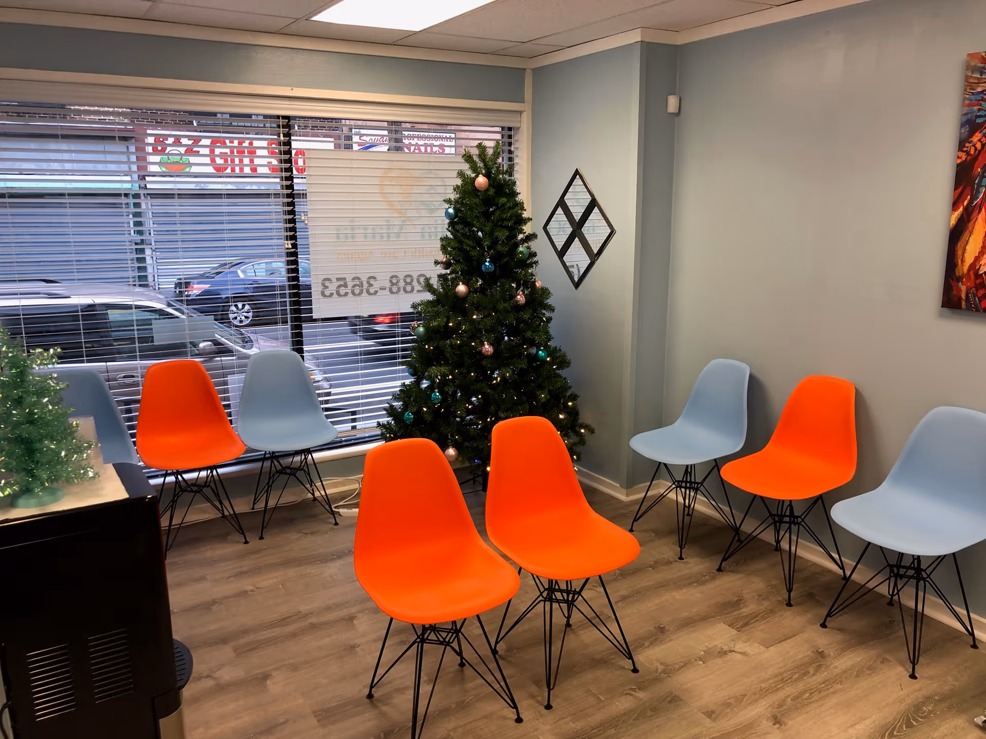 Small waiting area with orange and blue chairs, Christmas tree near window