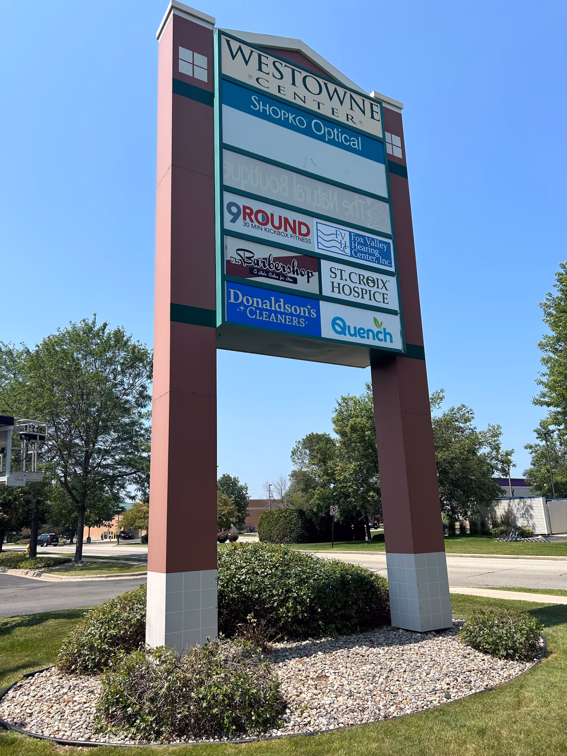 Tall outdoor sign with multiple business listings, including St. Croix Hospice, in a landscaped lot.
