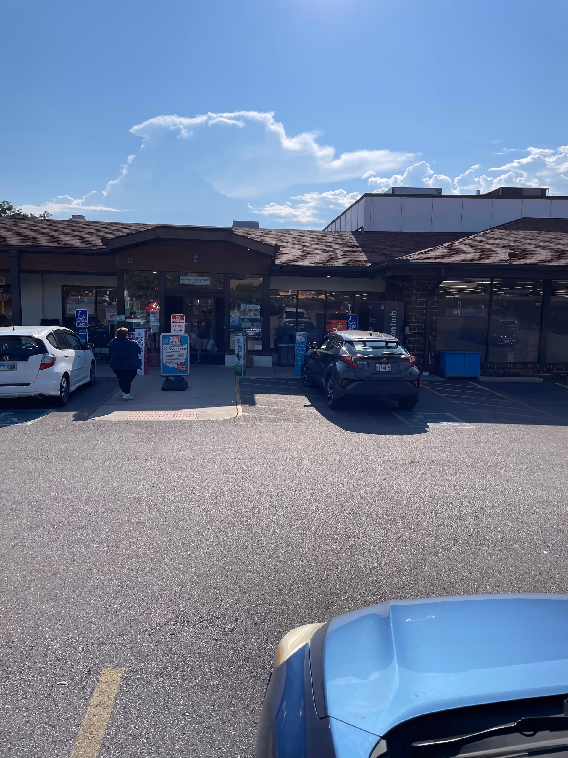 Front view of Discount Drug Mart storefront with parked cars and shoppers at entrance