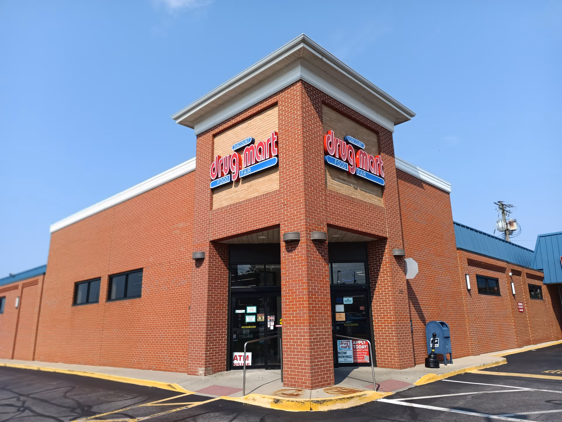 Exterior view of a brick Discount Drug Mart storefront under a clear sky.