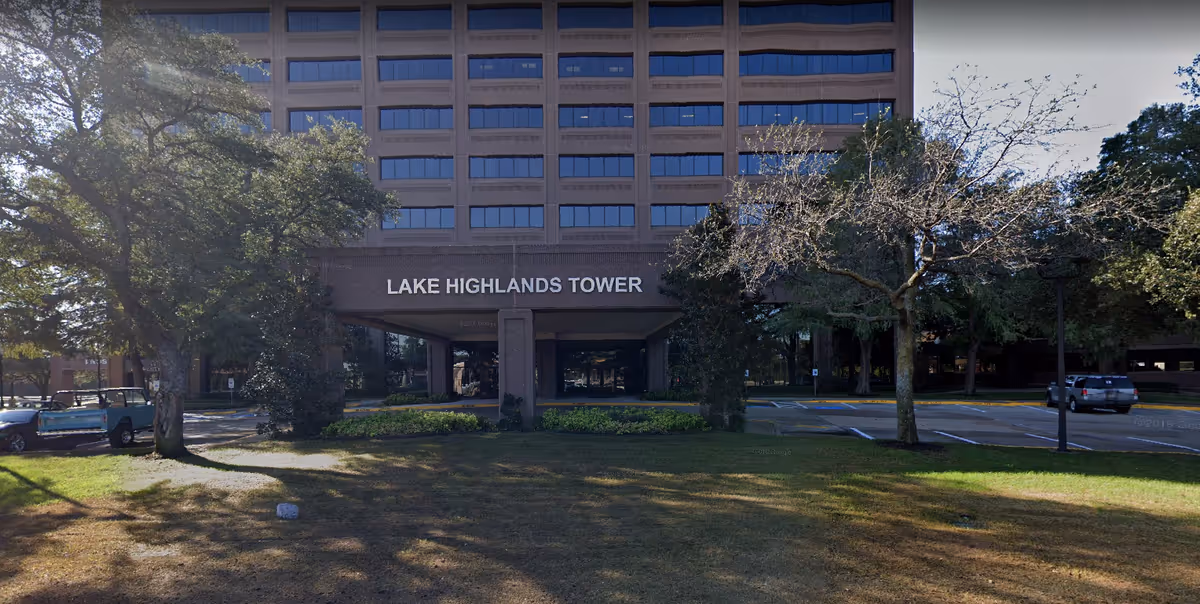 Front view of a tall brick building with a covered entrance labeled Lake Highlands Tower.