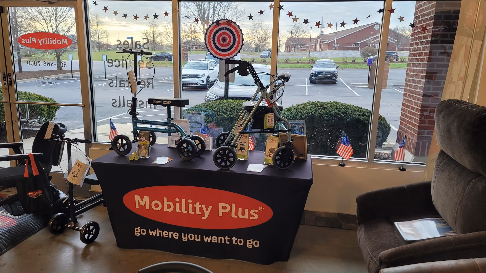 Indoor Mobility Plus display table with walkers and scooters near a window.