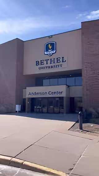 Exterior view of Bethel University building with glass entrance and driveway.