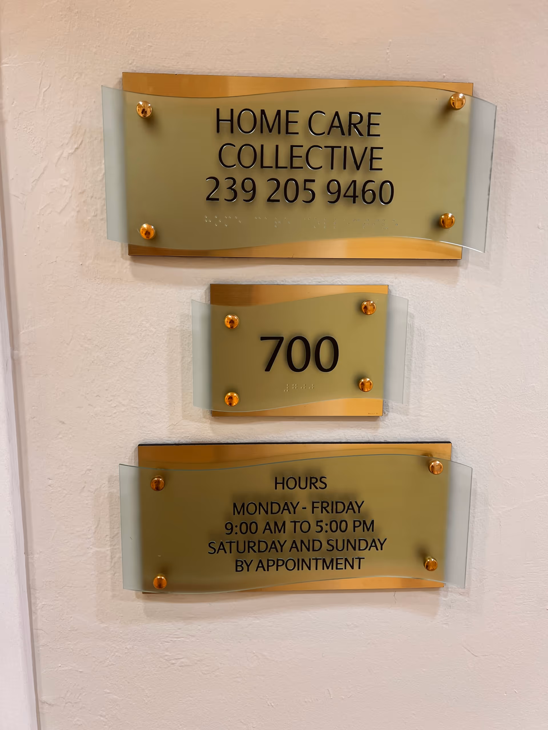 Gold-toned wall plaques display address, phone number, and hours for Home Care Collective.