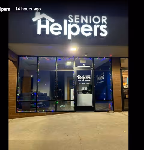 Front exterior of Senior Helpers facility with large lit sign and glass entrance door.