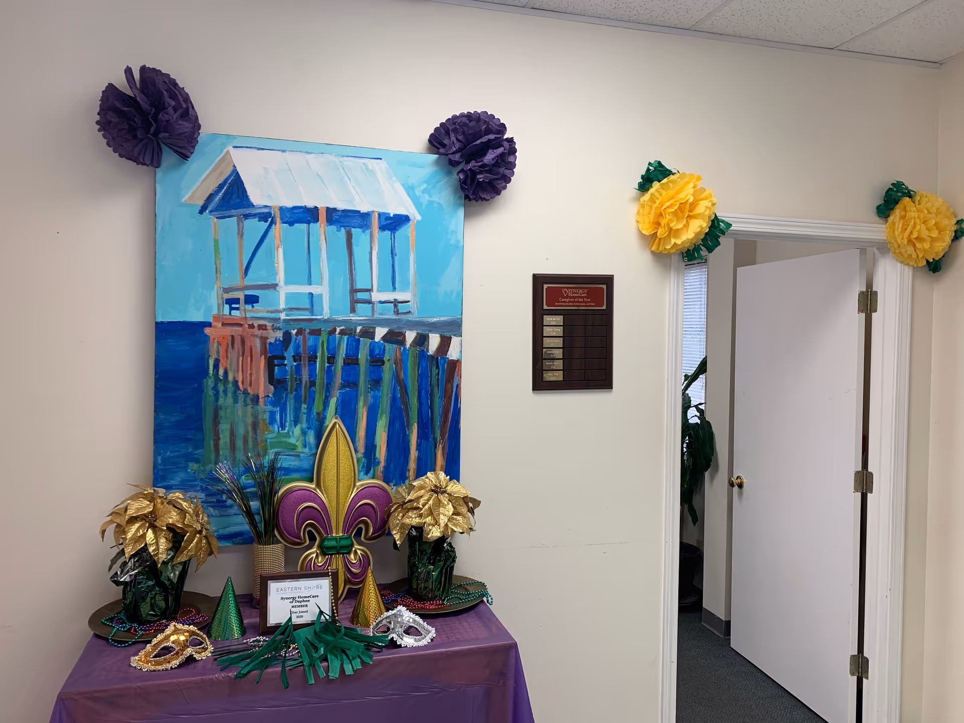 Indoor hallway with wall art and Mardi Gras decorations on a table.