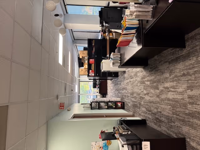 Office-like reception area with desks, filing cabinets, and shelves in a bright hall.