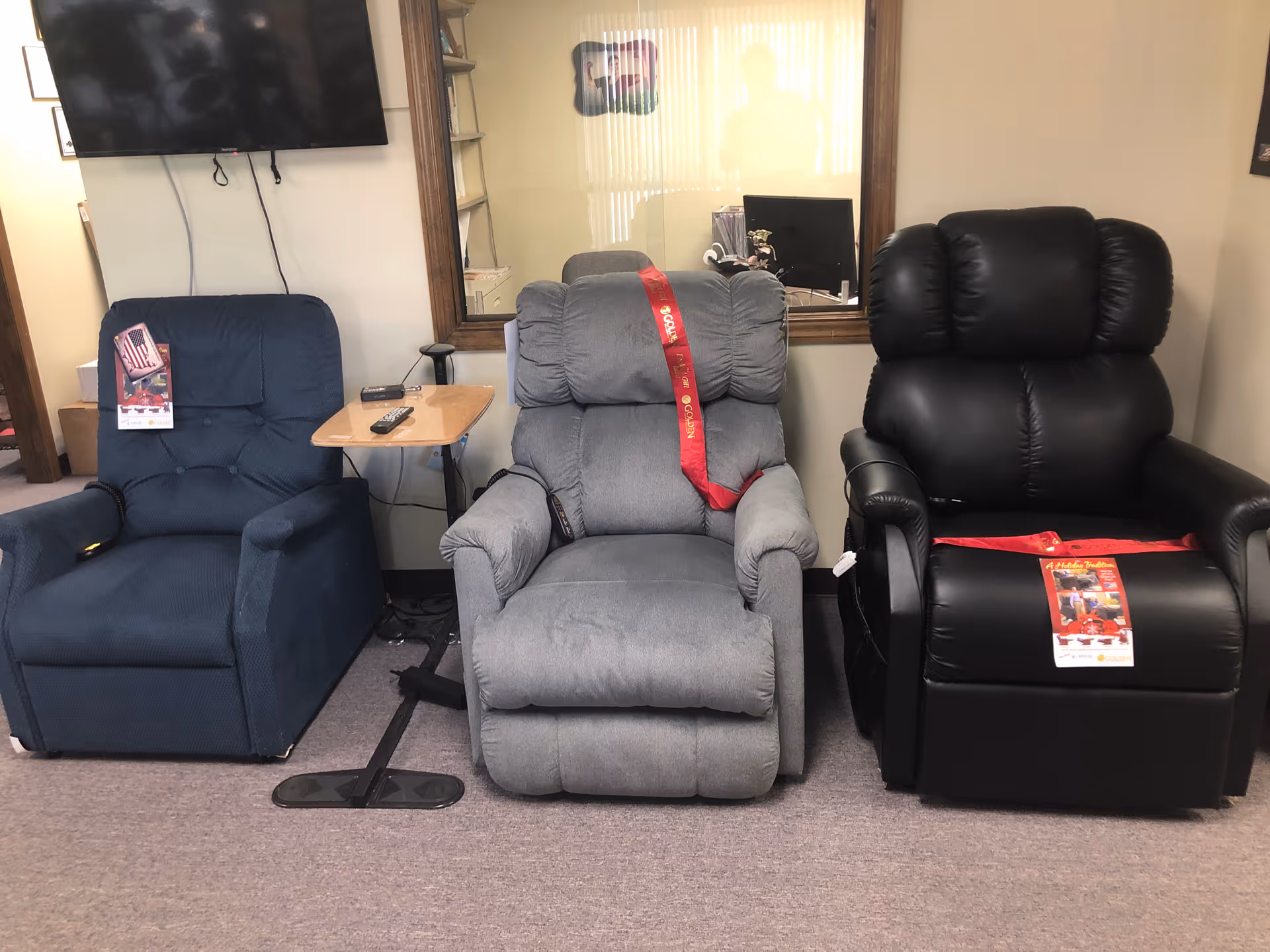 Three recliner chairs arranged in a lounge with a wall-mounted TV.