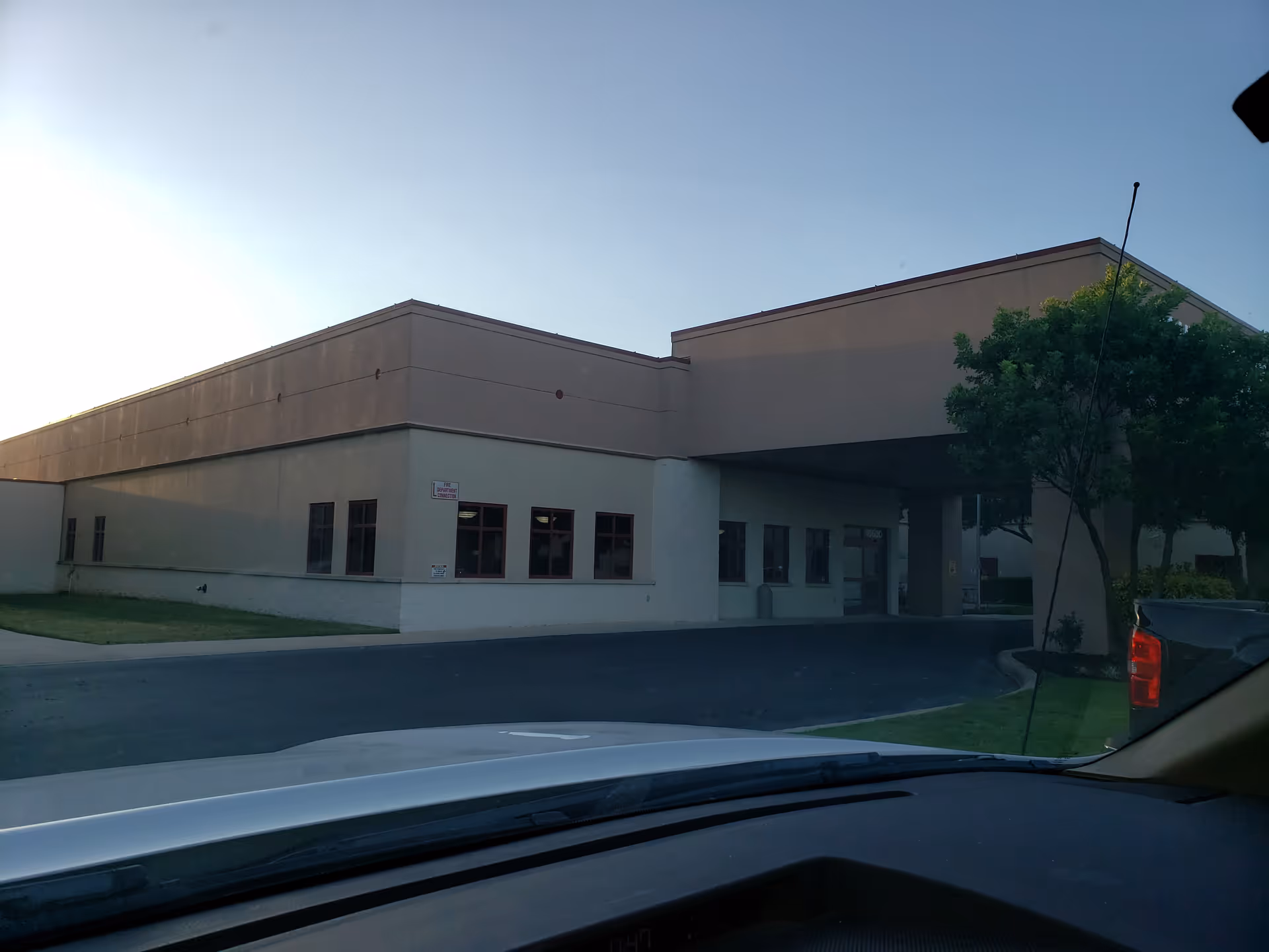Exterior view of a single-story medical facility with a driveway and trees.
