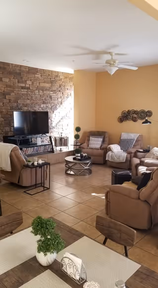Living room with beige seating, coffee tables, and a stone accent wall.