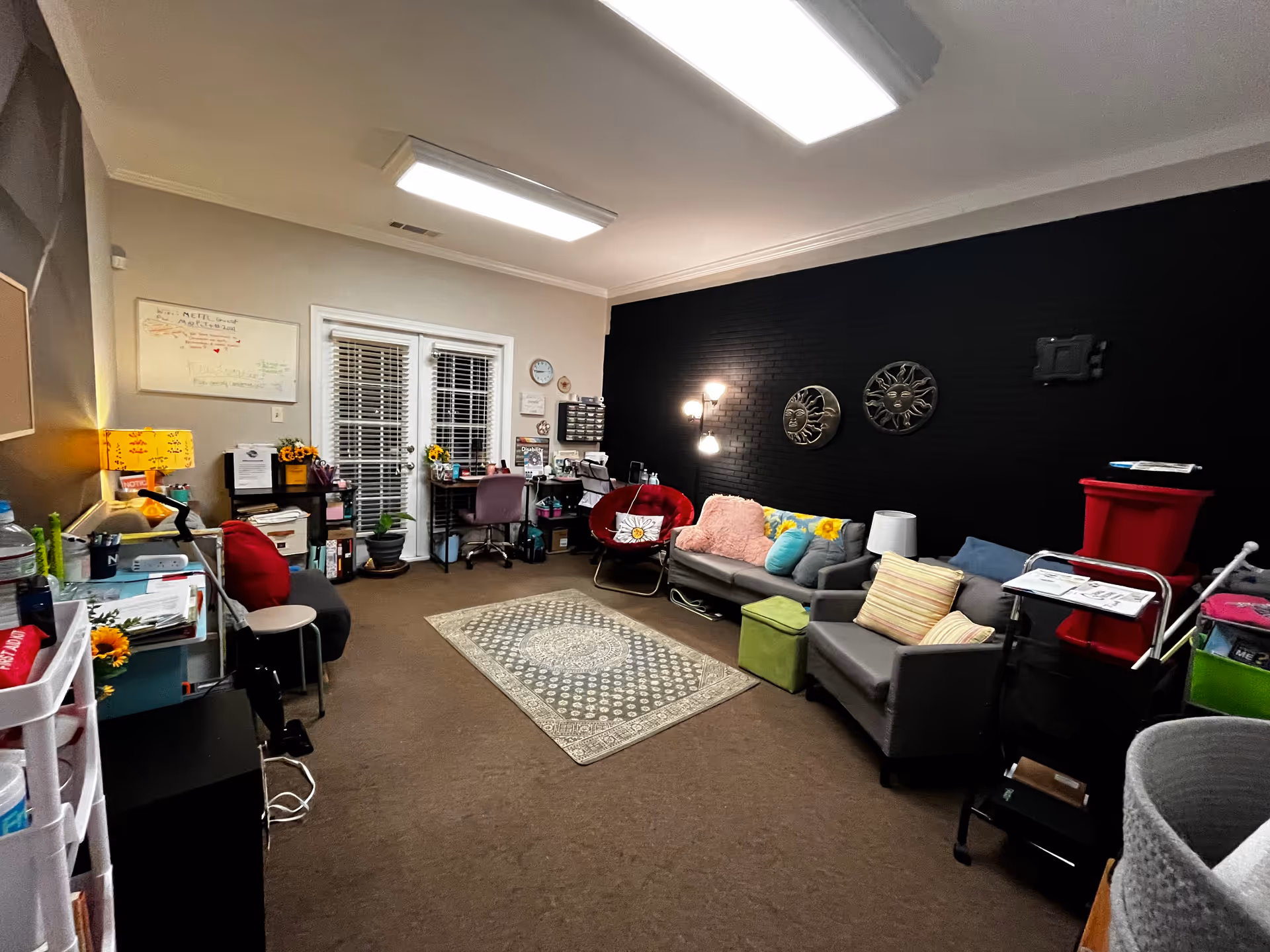 Interior senior living lounge with sofas, chairs, rug, and dark accent wall.