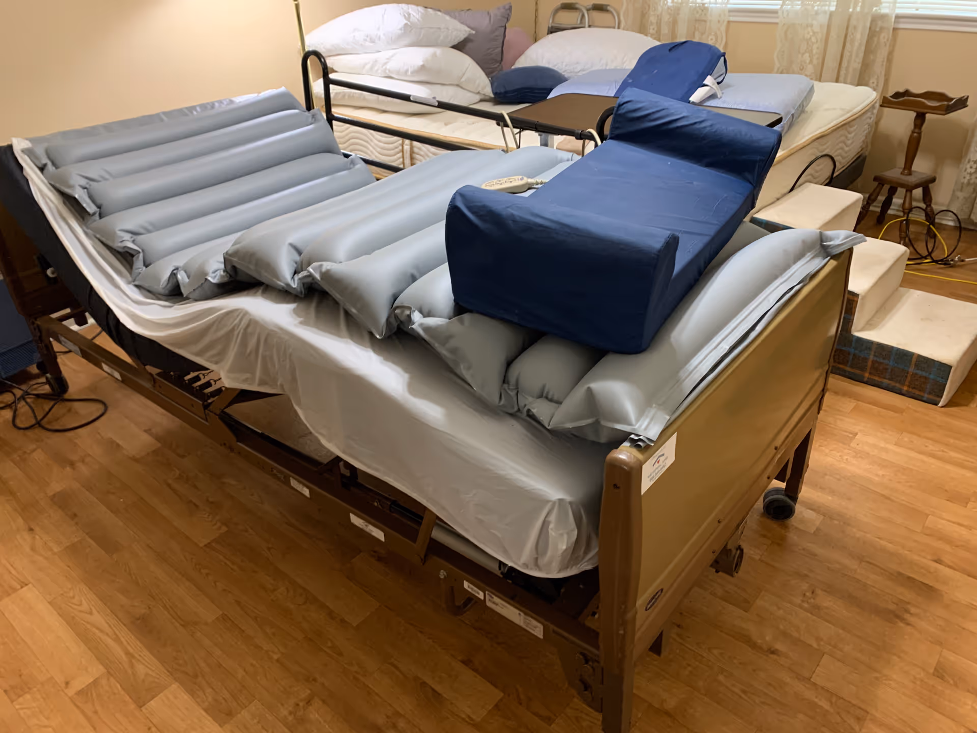 In a senior living room, a hospital-style adjustable bed with blue pillows.